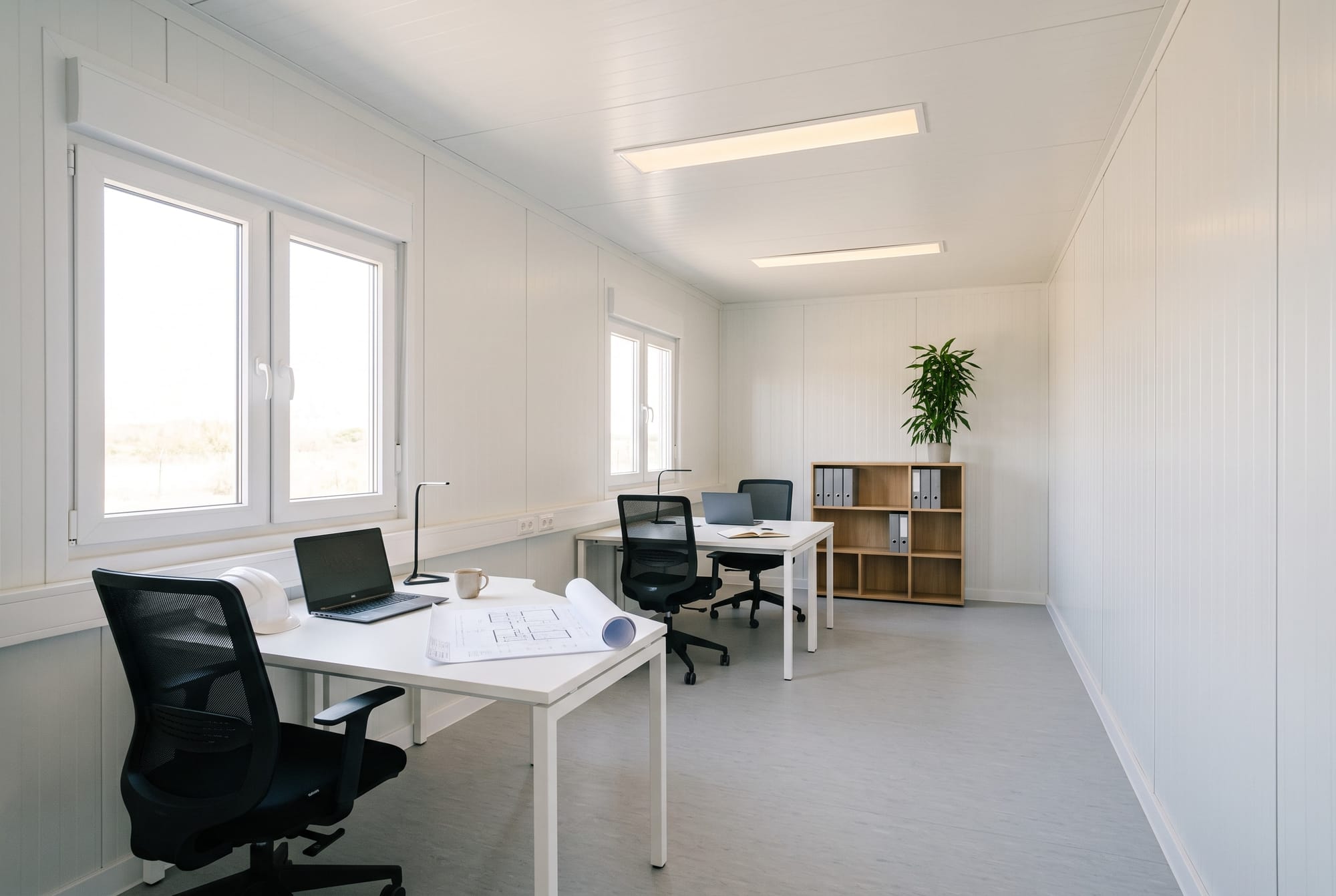 Interior de un módulo preparado como oficina, con dos puestos de trabajo junto a las ventanas.